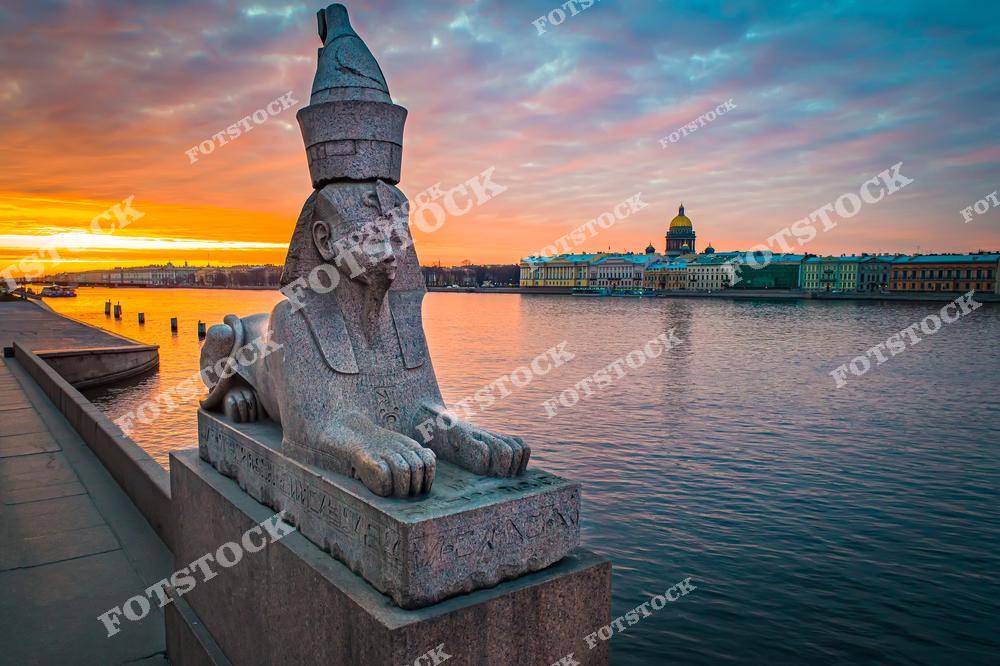 Фотография вечернего Санкт-Петербург, Россия. На изображении запечатлены египетские сфинксы на Университетская набережная, расположенной на Васильевский остров, на фоне реки Нева. Фотоснимок передаёт атмосферу вечернего Петербурга: мягкий свет, спокойная вода и величественные скульптуры подчёркивают архитектурный облик города. Фото отражает уникальное сочетание истории, архитектуры и романтики северной столицы, а также туристическую привлекательность Санкт-Петербурга как одного из знаковых городов России.